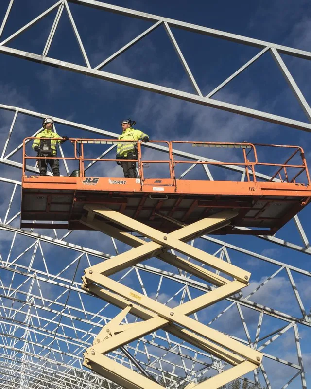 Dos operarios en una plataforma de tijera durante el montaje de una estructura metálica